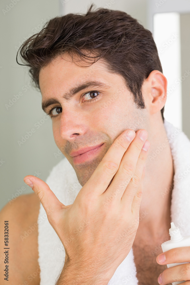 Obraz premium Man applying moisturizer on face