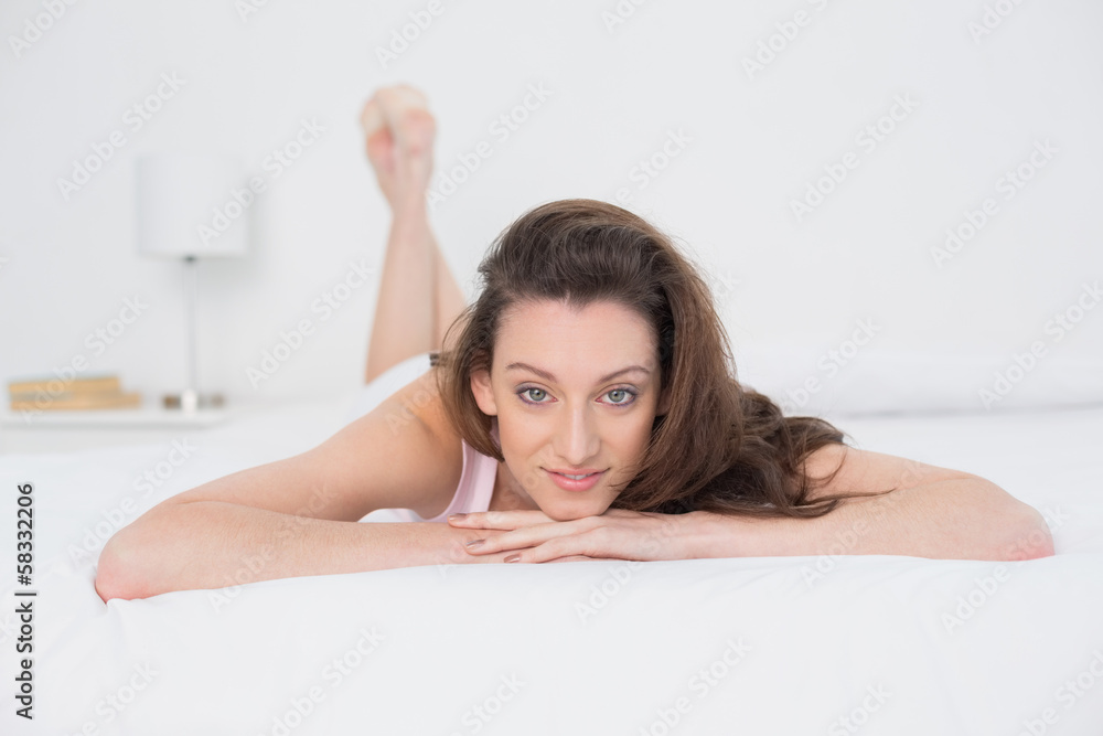 Full length portrait of a smiling woman resting in bed Full length portrait of a smiling woman resting in bed