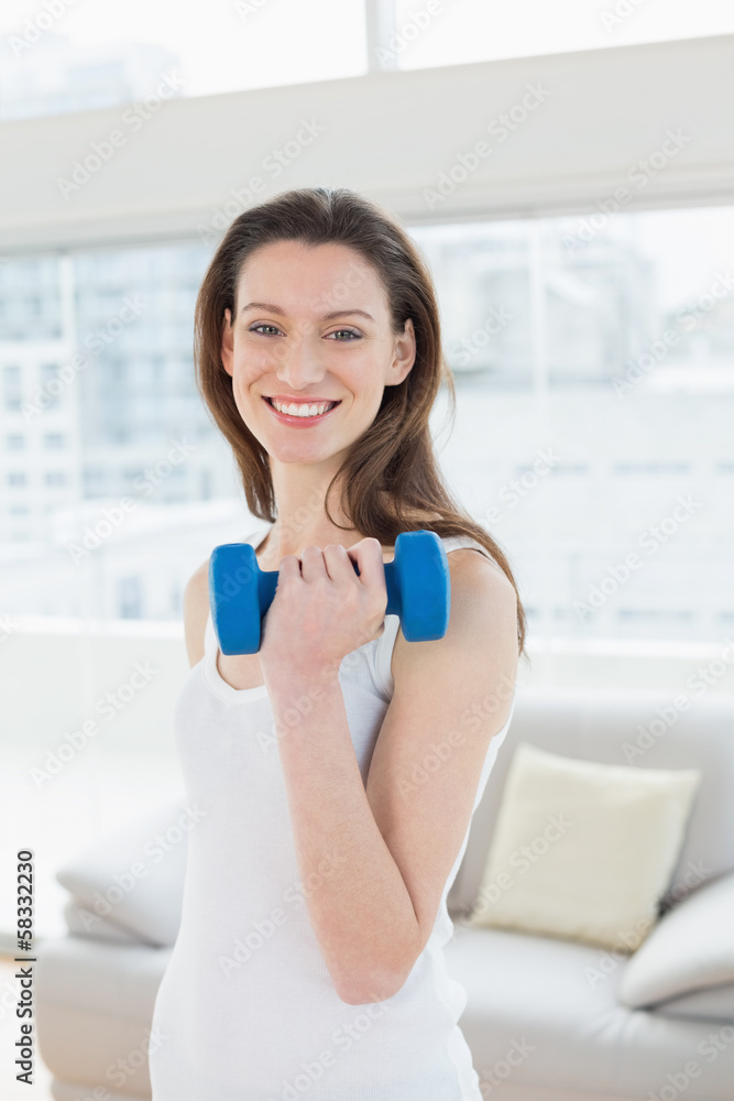 Fit woman exercising with dumbbell in fitness studio