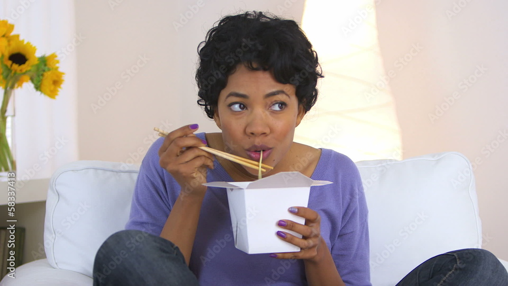 African American woman eating up noodles from chinese take out African American woman eating up noodles from chinese take out