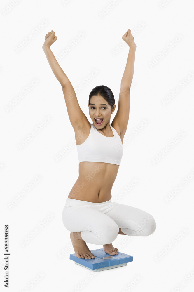 Woman on a weight scale and looking excited Woman on a weight scale and looking excited