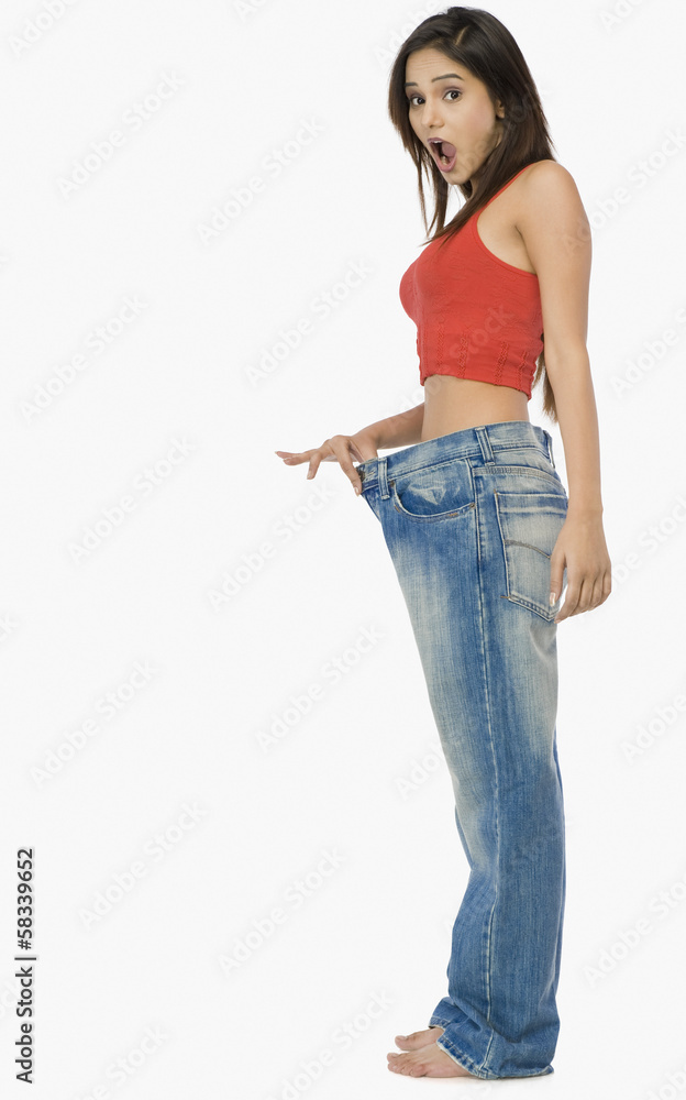 Woman pulling jeans from waistline to show weight loss Woman pulling jeans from waistline to show weight loss