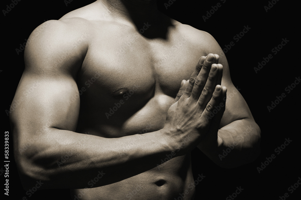 Mid section view of a muscular man meditating Mid section view of a muscular man meditating