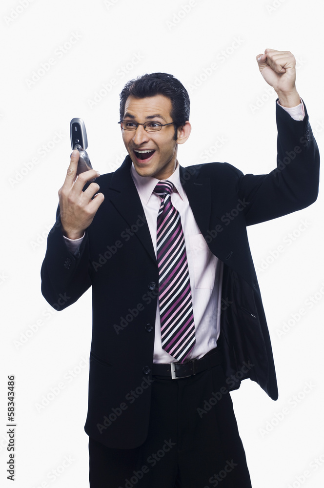 Businessman clenching fist while reading a text message on a mobile phone Businessman clenching fist while reading a text message on a mobile phone