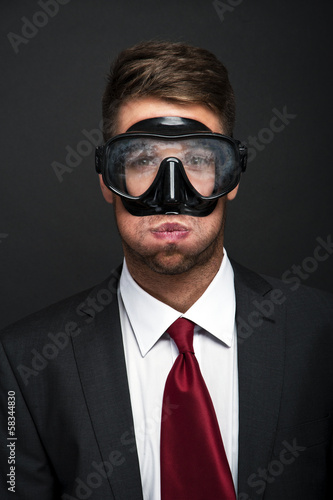Businessman on a black background smiling wearing a snorkel and