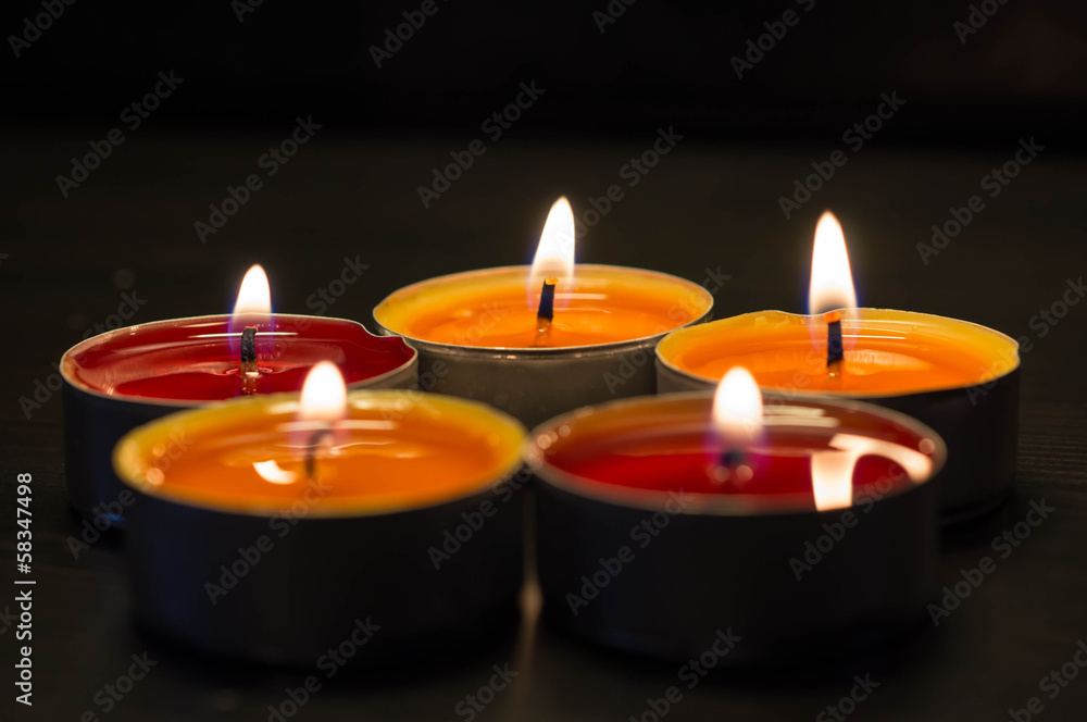 Five burning candles against a dark background