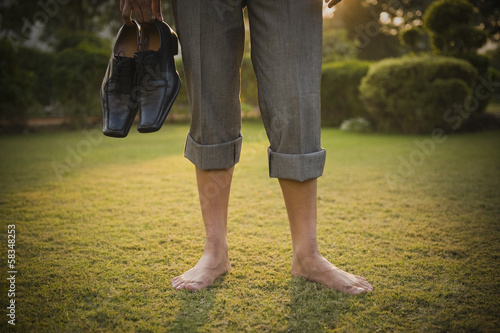 Photography Low section view of a businessman holding shoes in a park