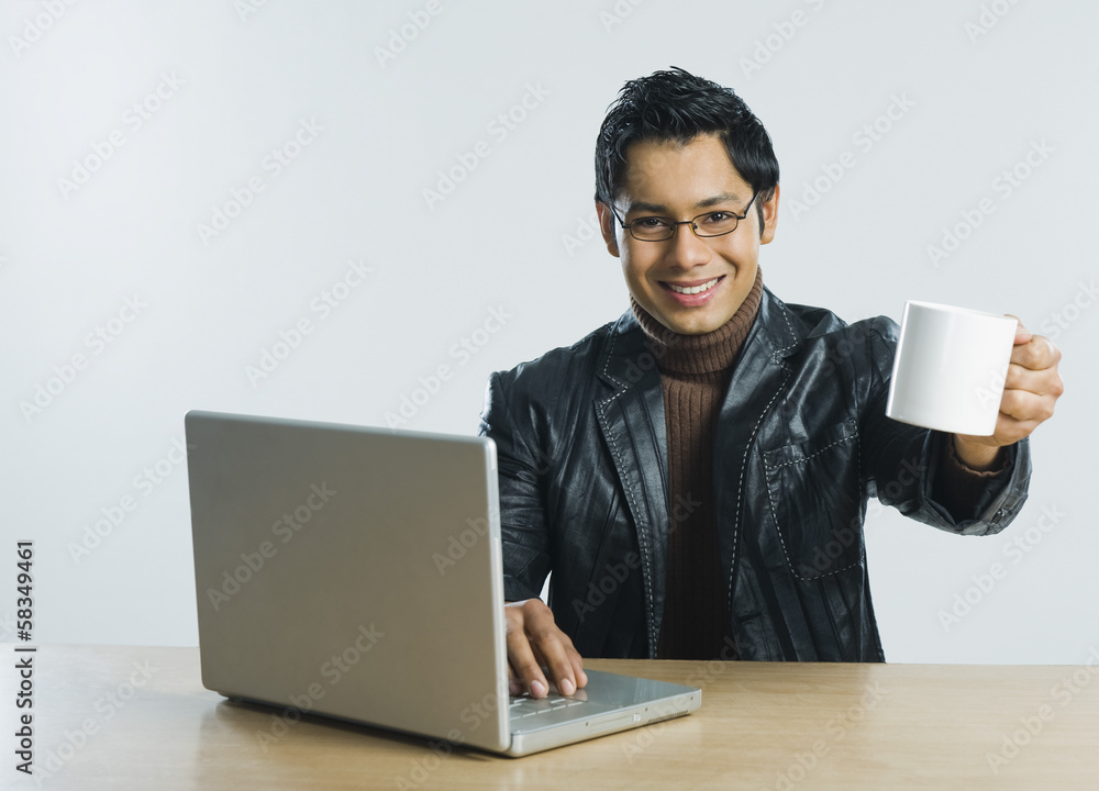 Man working on a laptop and drinking a cup of coffee Man working on a laptop and drinking a cup of coffee