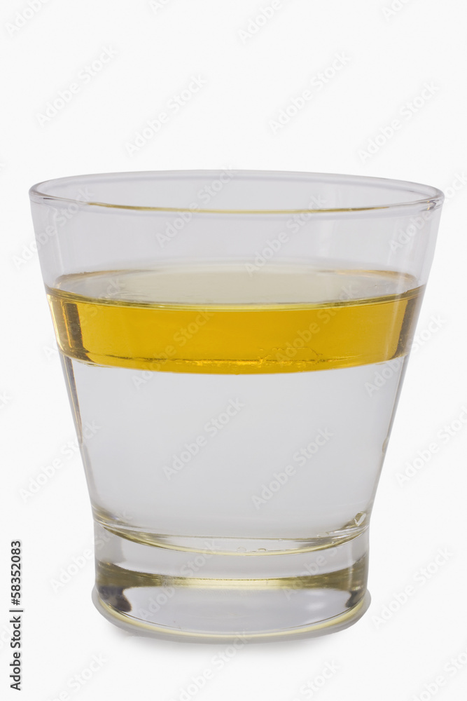 Oil floating on water surface in a glass Oil floating on water surface in a glass