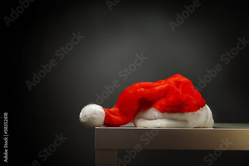 Santa hat laying on table against black background