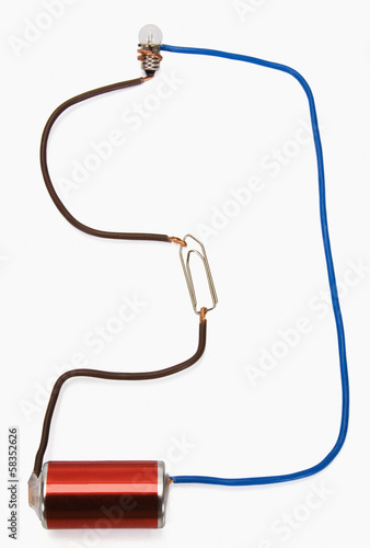 Close-up of a battery connected to light bulb and a paperclip