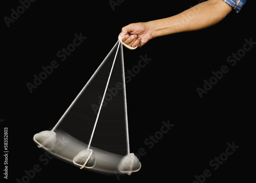 Close-up of a person's hand swinging a stone pendulum