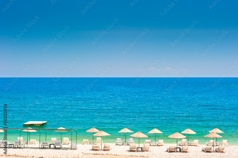 Obraz premium empty beach with white wicker umbrellas