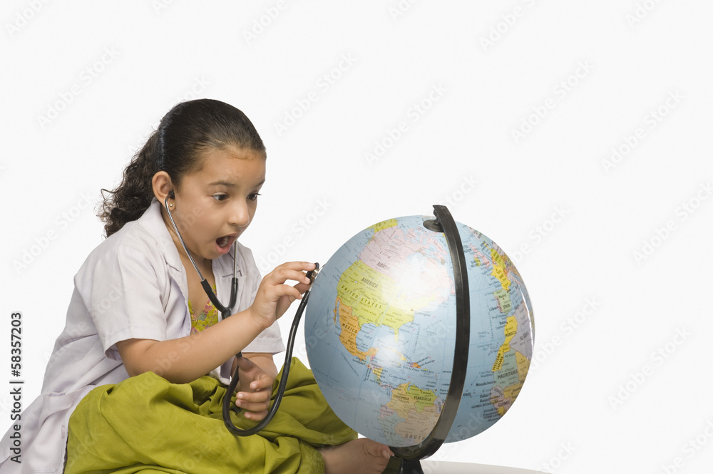 Girl examining a globe with a stethoscope Girl examining a globe with a stethoscope