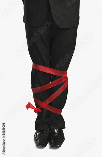 Businessman's legs tied up with a ribbon