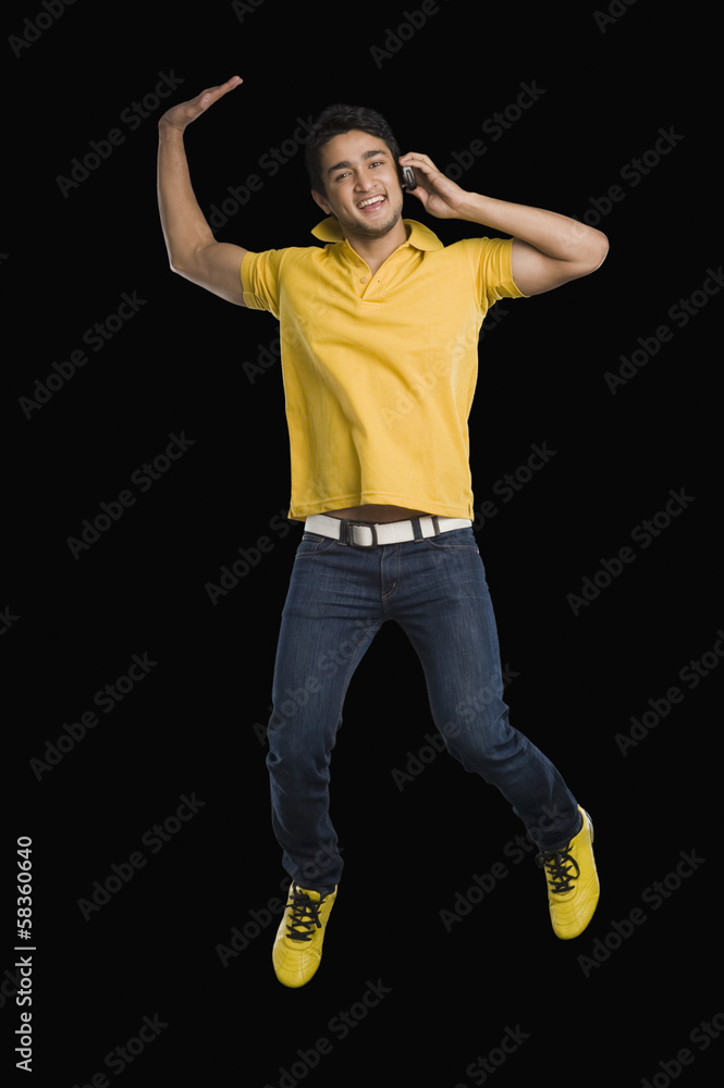 Man talking on a mobile phone and jumping Man talking on a mobile phone and jumping