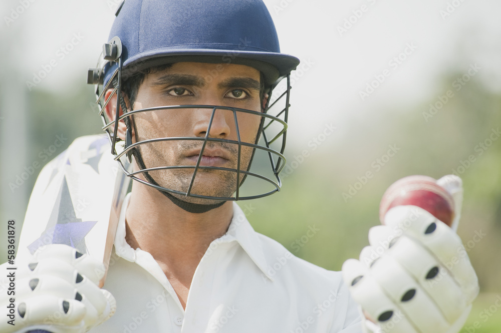 Cricket batsman holding a cricket bat with a cricket ball foto de Stock