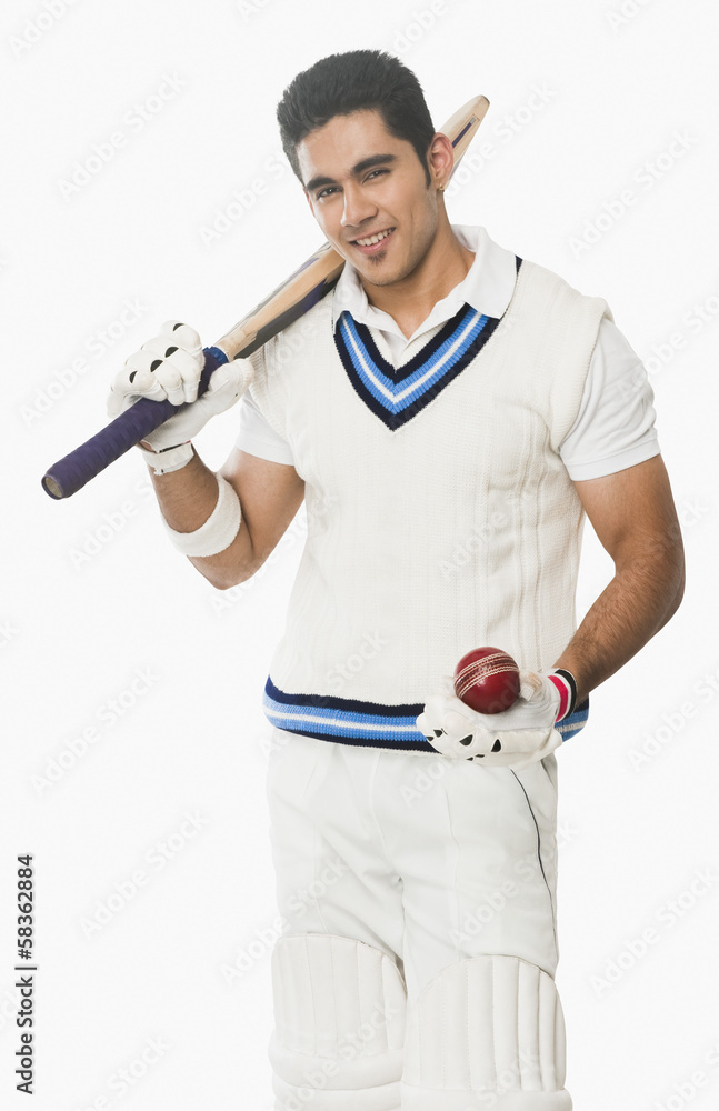 Portrait of a cricket batsman holding a bat and a ball Portrait of a cricket batsman holding a bat and a ball