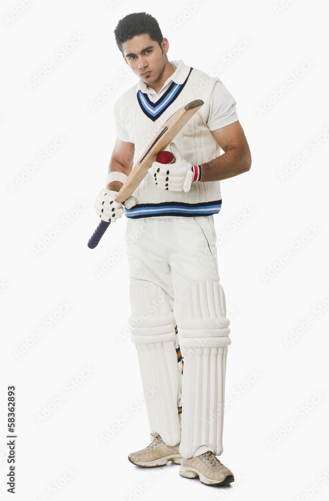 Cricket batsman holding a ball and bat Cricket batsman holding a ball and bat