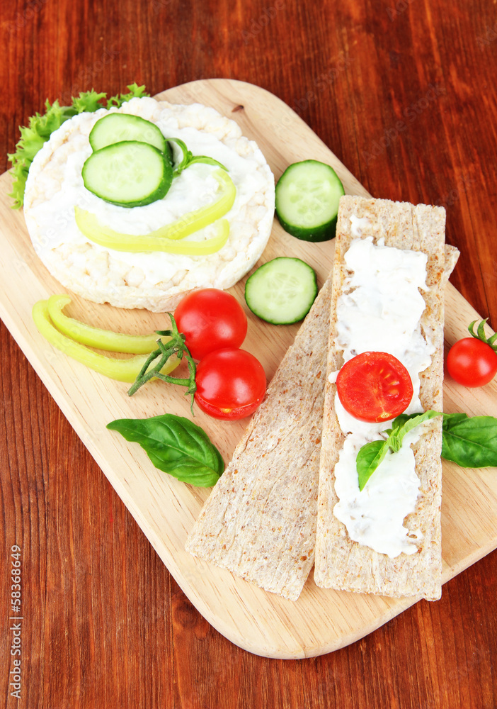 Tasty crispbreads with vegetables on wooden background Tasty crispbreads with vegetables on wooden background