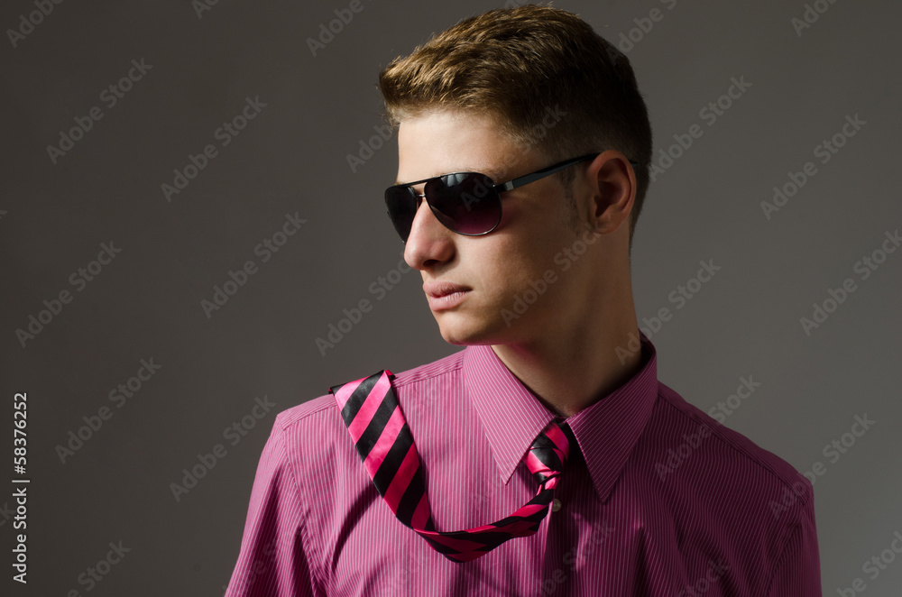 Fototapeta premium Handsome young man with sunglasses wearing a pink shirt