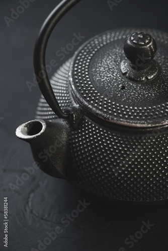 Close-up of black cast-iron asian teapot, vertical shot