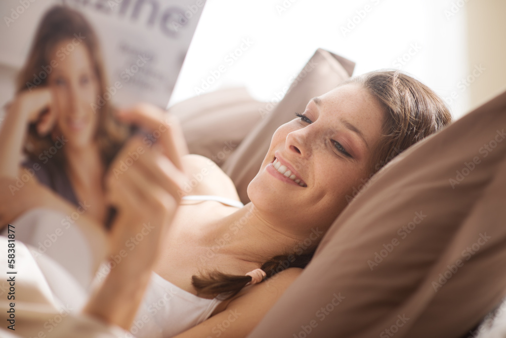 Woman relaxing in bed with magazine Woman relaxing in bed with magazine