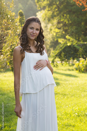Pregnant woman in long dress in park