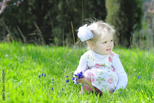 little girl on a green meadow in a beautiful dress