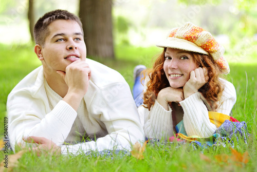 Young beautiful couple on green grass in autumn