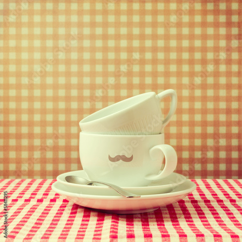 Coffee cups with hipster mustache on checked tablecloth