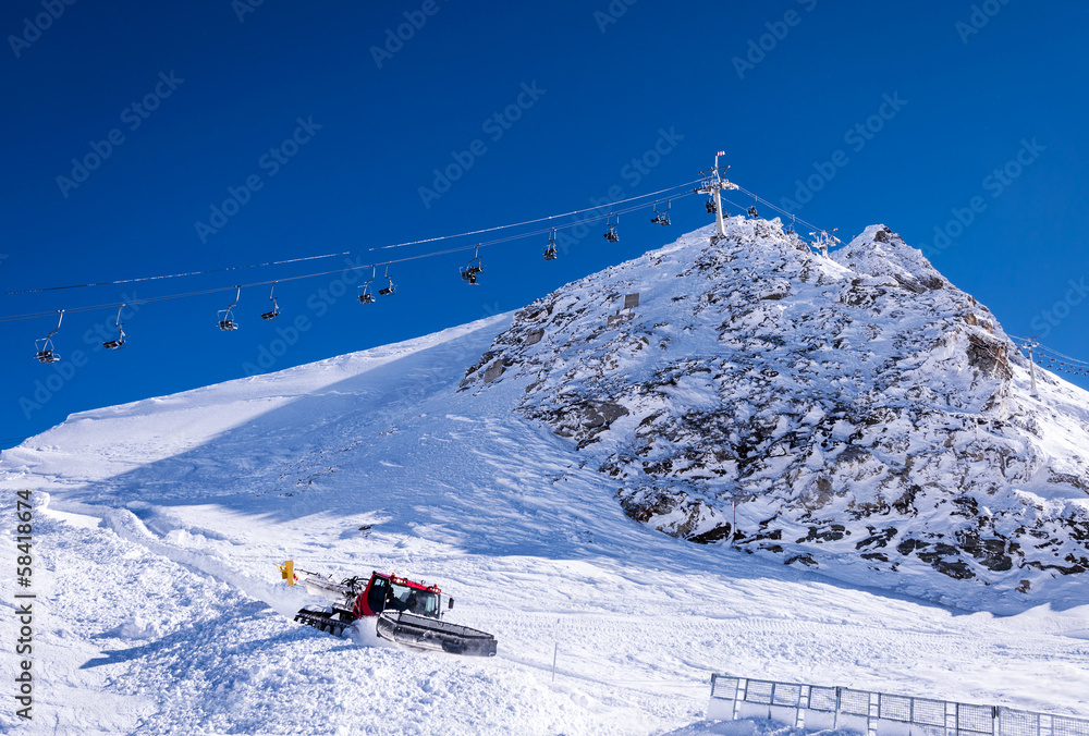 Chair lift and snow groomer in Alps