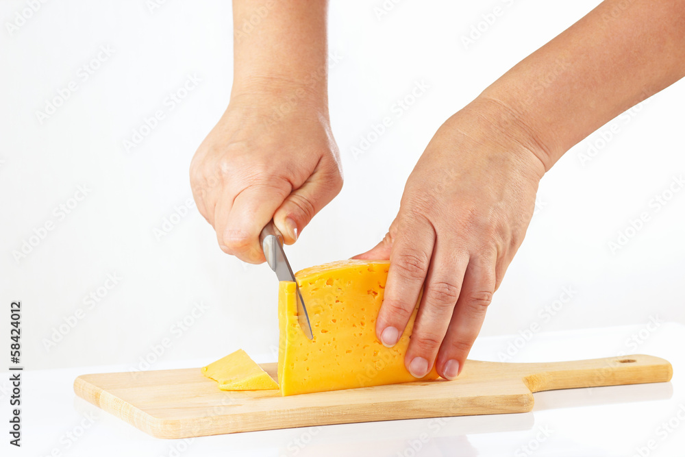 Female hand with a knife sliced cheese on a white background Female hand with a knife sliced cheese on a white background