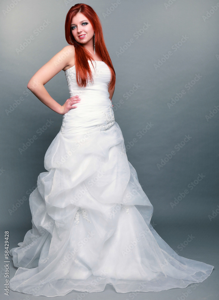 Happy beautiful red haired bride on gray background