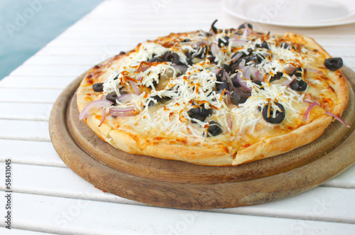 mediterranean pizza on wooden round plate
