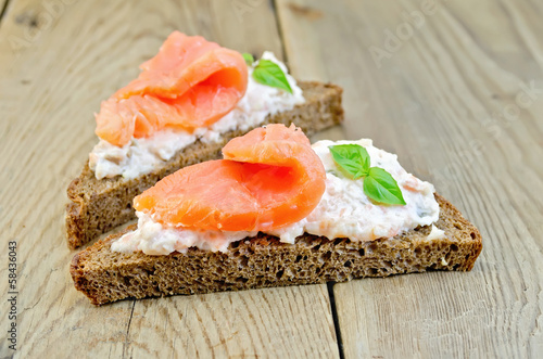 Sandwiches on bread with salmon and basil on board
