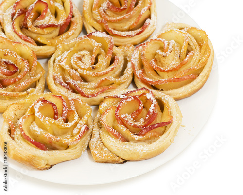 Sweet rolls with apples in the form of roses on plate on white b