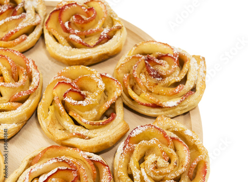 Sweet rolls with apples in the form of roses on wooden board on