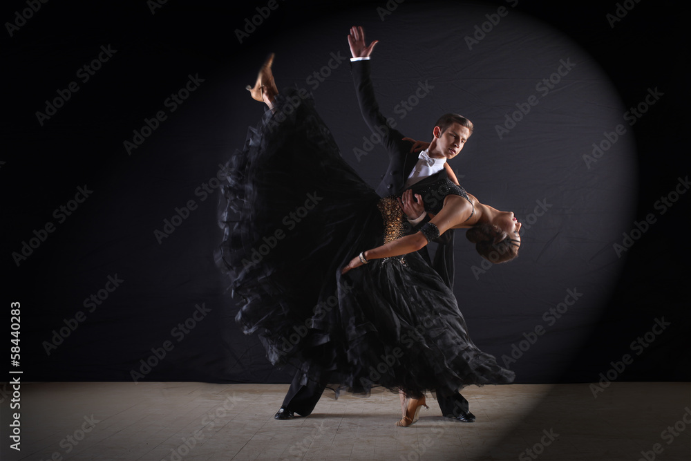 Latino dancers in ballroom against black background