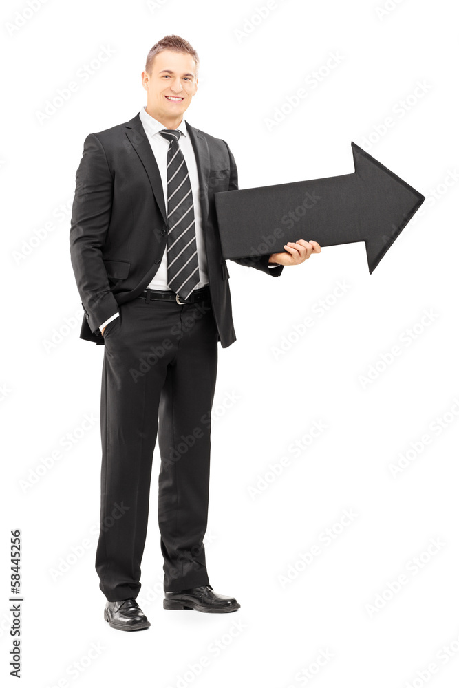 Smiling businessman in black suit holding a big arrow