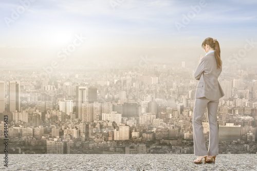 Asian businesswoman on roof looking at city