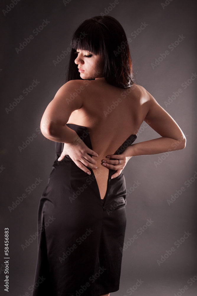 Fototapeta premium Portrait of sexy woman from back in unbuttoned dress