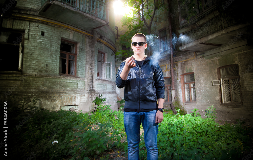 portrait of young man in sunglasses holding reeky cigarette