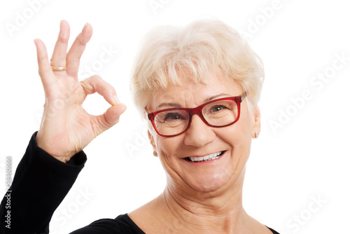 Happy old woman in eye glasses showing OK.