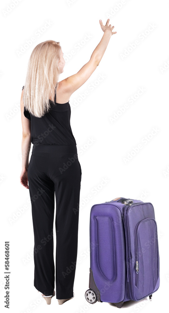 Back view of young blonde woman traveling with suitcas and point Back view of young blonde woman traveling with suitcas and point