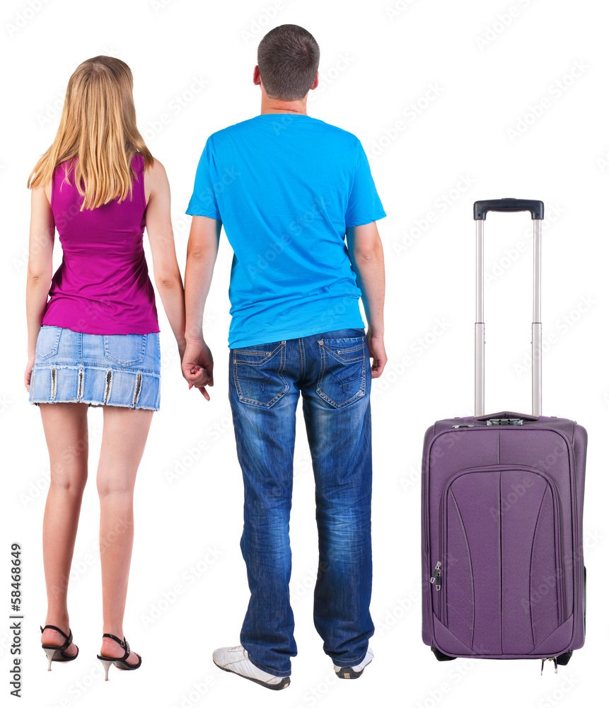 Back view of young couple traveling with suitcas . Back view of young couple traveling with suitcas .