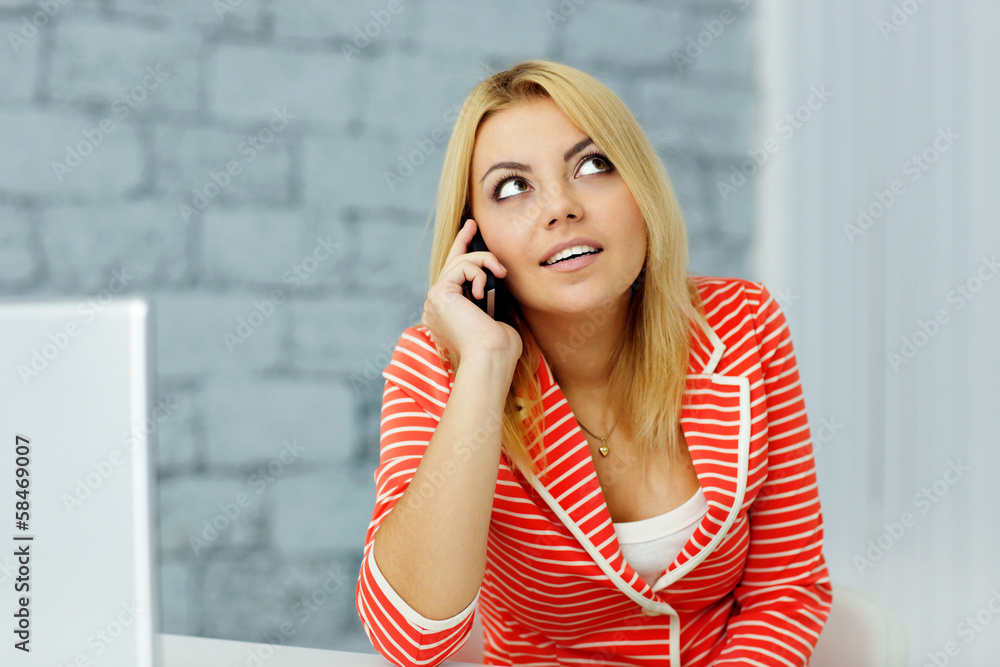 Fototapeta premium Young businesswoman talking on phone and looking up at copyspace