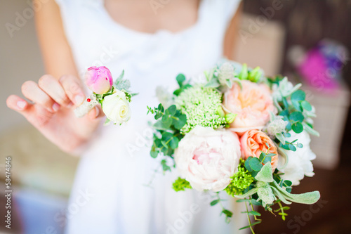 bride holding a wedding bouquet and a buttonhole