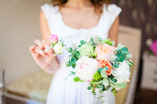 bride holding a wedding bouquet and a buttonhole