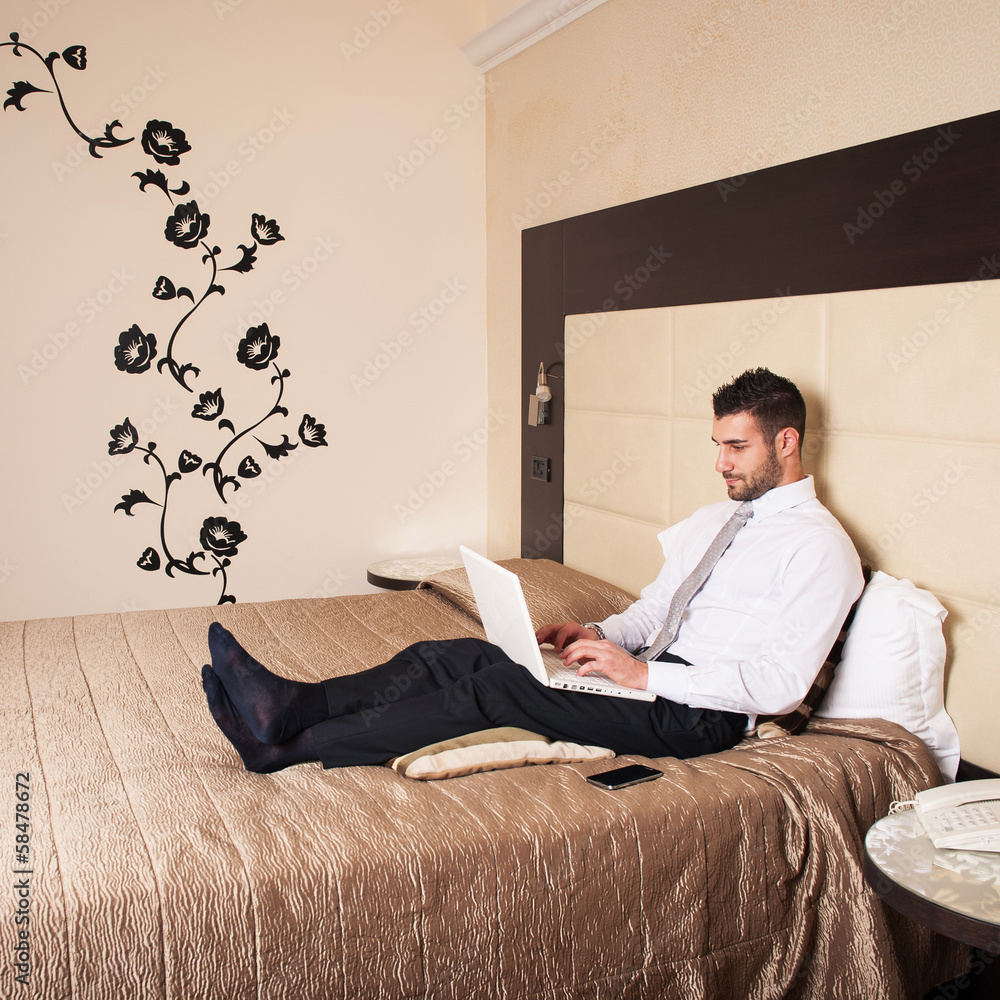 Young businessman working with computer in hotel room. Young businessman working with computer in hotel room.